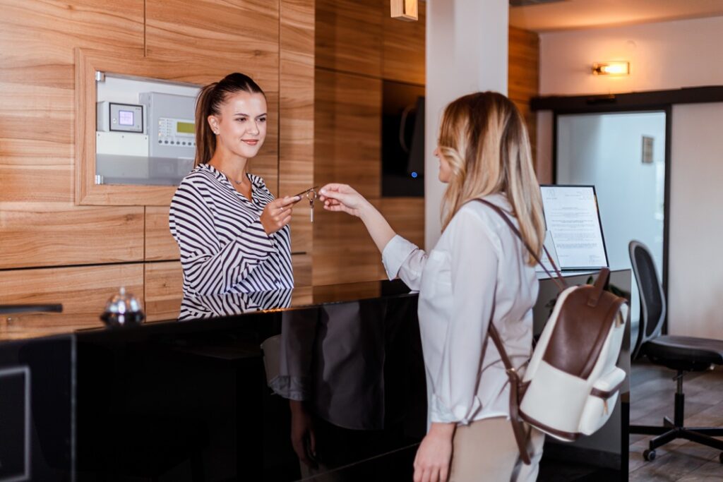 A hotel receptionist provides a room key to a guest at the front desk in a welcoming environment.